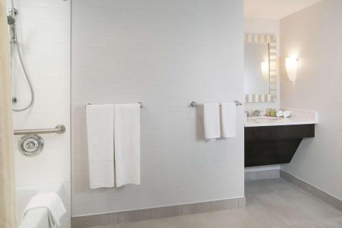东叙拉古DoubleTree by Hilton Hotel Syracuse的带淋浴、白色毛巾和盥洗盆的浴室