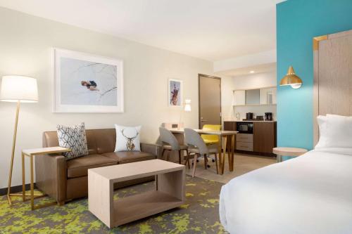 博尔德博尔德希尔顿合博套房酒店的酒店客房配有床、沙发和桌子。