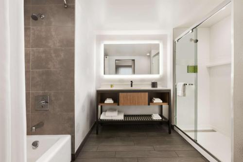 博尔德博尔德希尔顿花园酒店的一间带水槽、浴缸和镜子的浴室