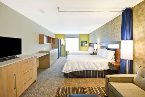 迪凯特Home2 Suites By Hilton Decatur Ingalls Harbor的一间酒店客房,配有一张床和一台电视