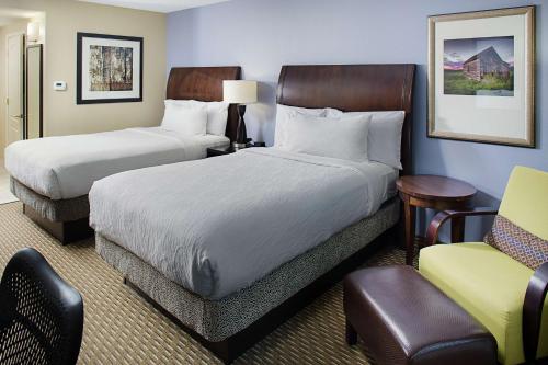 莫里斯维尔Hilton Garden Inn Raleigh Durham Airport的酒店客房,配有两张床和椅子