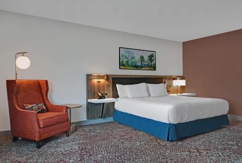 麦迪逊Hilton Garden Inn Madison Huntsville Airport的配有一张床和一把椅子的酒店客房