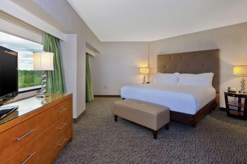 奥本希尔斯Embassy Suites by Hilton Auburn Hills的配有一张床和一台平面电视的酒店客房