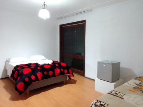 乌鲁瓜亚纳Pousada A Cabana的一间卧室配有一张带黑色和红色毯子的床
