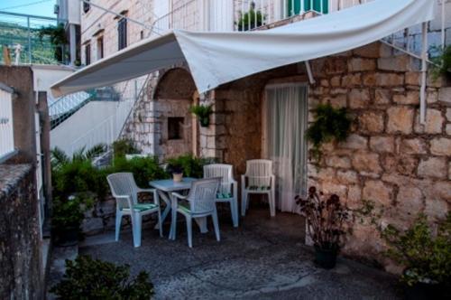 科米扎Marina Rooms的一个带桌椅的白色遮阳伞下庭院