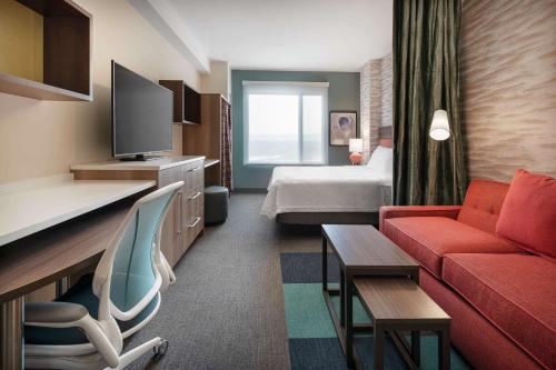 丹佛Home2 Suites By Hilton Denver Downtown Convention Center的酒店客房配有红色的沙发和床。