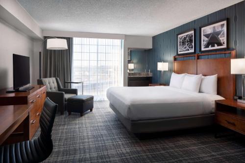 奥斯汀Embassy Suites by Hilton Austin Central的酒店客房配有一张床、一把椅子和一台电视。