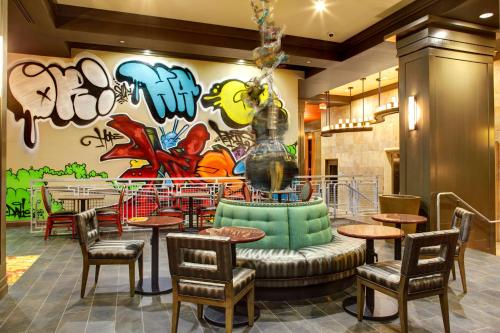 奥斯汀首府奥斯汀大学汉普顿套房酒店的一间餐厅配有桌椅和涂鸦墙