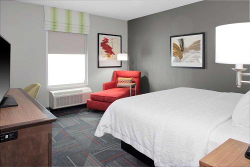 哥伦布Hampton Inn & Suites Columbus Scioto Downs的酒店客房,配有一张床和一张红色椅子