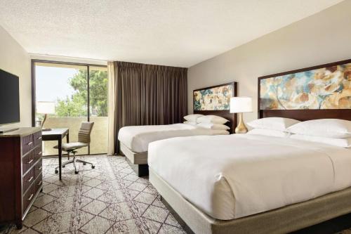 亚特兰大亚特兰大东北/北湖希尔顿逸林酒店的酒店客房设有两张床、一张桌子和一台电视。