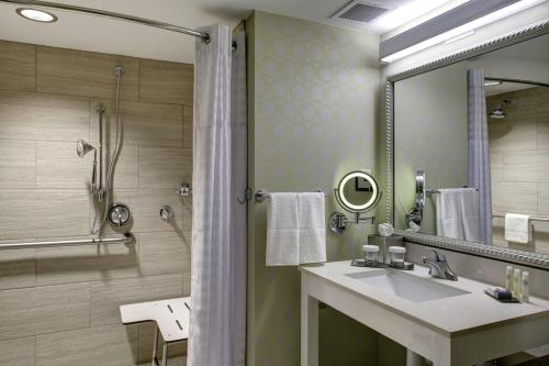 比洛克西比洛克西希尔顿逸林酒店的浴室配有盥洗盆和带镜子的淋浴