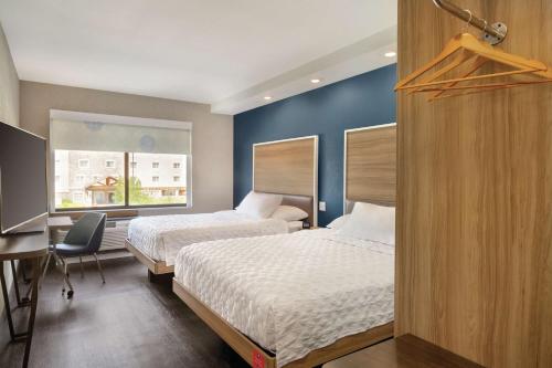 默里迪恩Tru By Hilton Meridian Boise West Id的酒店客房设有两张床、一张书桌和一个窗户。