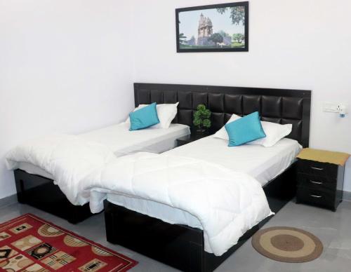 克久拉霍Khajuraho Glory Homestay的一间卧室配有两张带白色和蓝色枕头的床