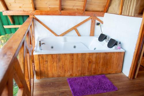 圣奥古斯丁Antahkarana Casa Hotel的紫色地毯的客房内设有浴缸
