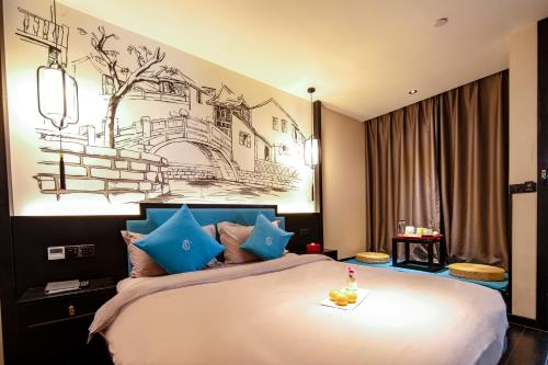 昆明龚禧里·禧见酒店(昆明东风东路大树营地铁站店)的一间卧室配有一张带蓝色枕头的大床
