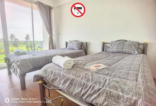 Ban Khlong KrangYYK Hostel 24H的卧室内的两张床,墙上有标志
