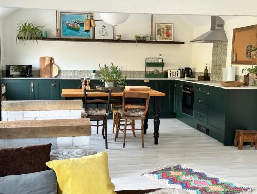 BlackwaterThe Wimberry的厨房配有绿色橱柜和木桌