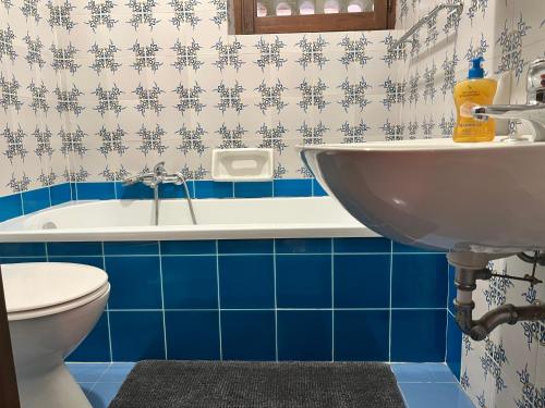阿尔盖罗Villa Margherita的浴室设有水槽和蓝色瓷砖浴缸。