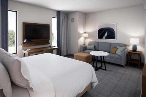 曼特卡Staybridge Suites Manteca, an IHG Hotel的酒店客房配有床、沙发和电视。