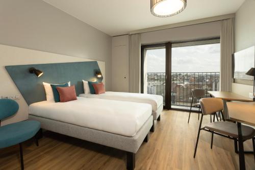 安特卫普Adagio Antwerp City Center的酒店客房设有两张床和一张桌子。