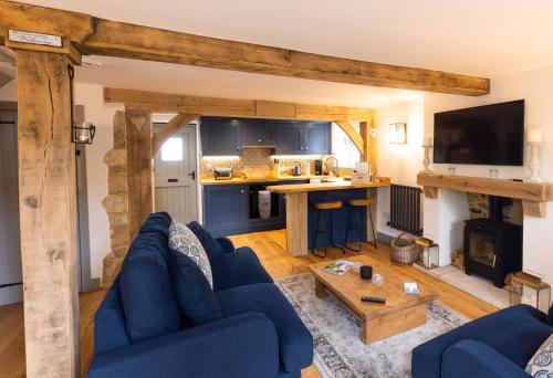BledingtonCotswold cottage with hot tub的一间带蓝色沙发的客厅和一间厨房