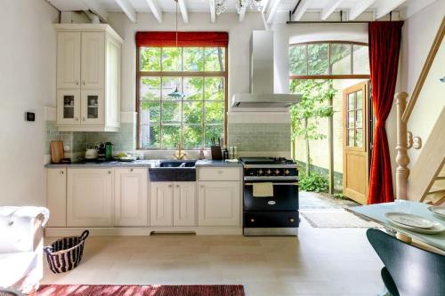 安特卫普Carriage House in quiet ecological garden的厨房配有白色橱柜和黑炉。