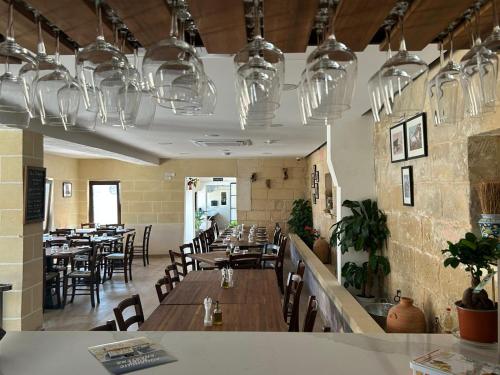 圣保罗湾城Ta' Gingel Farm Agriturisim B&B. Malta的餐厅设有木桌和椅子及灯