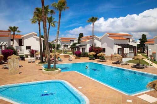 卡兰博希Nuramar Resort & Villas的一座房子前面的大型游泳池,里面种有棕榈树
