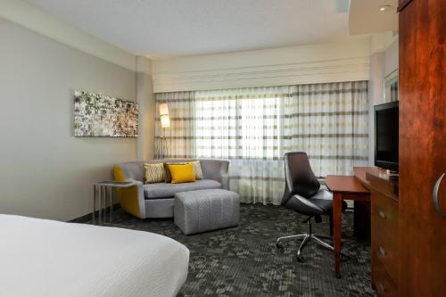 休斯顿休斯顿广场万怡酒店的酒店客房配有一张床、一张沙发和一张书桌。