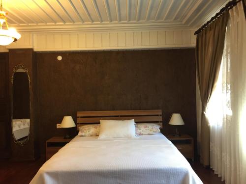 古雷Konak Lapeistra Hotel的一间卧室配有一张带两盏灯的大型白色床。