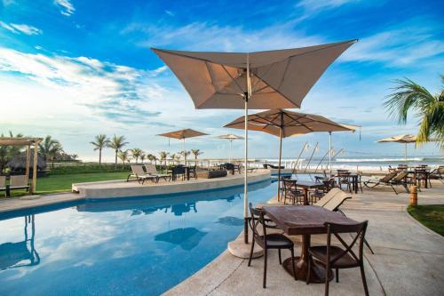 阿卡普尔科Mishol Bodas Hotel & Beach Club Privado的一个带桌椅和遮阳伞的游泳池