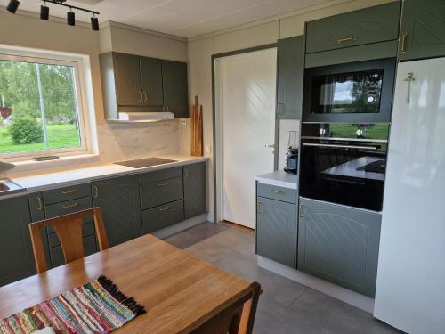 AlundaLantlig villa utanför Uppsala的厨房配有绿色橱柜和木桌