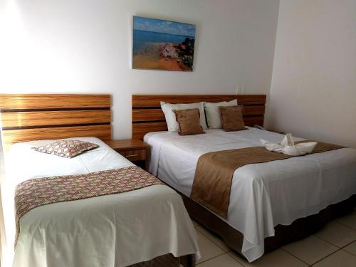 三玛丽亚镇Hotel Estrela Mares的酒店客房,配有两张带白色床单的床