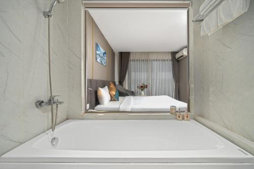芽庄索契酒店的浴室配有浴缸上方的镜子