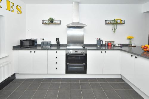 特伦特河畔斯托克Potter's Rest by YourStays的厨房配有白色橱柜和炉灶烤箱。