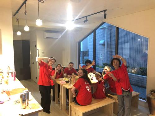 东京MAKOTO GUESTHOUSE -Enjoy your stay-的一群穿着红衬衫的人坐在桌子上