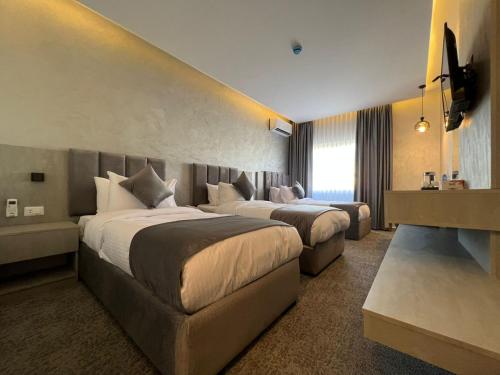 安曼Kaya Hotel Amman的酒店客房,设有两张床和一张沙发