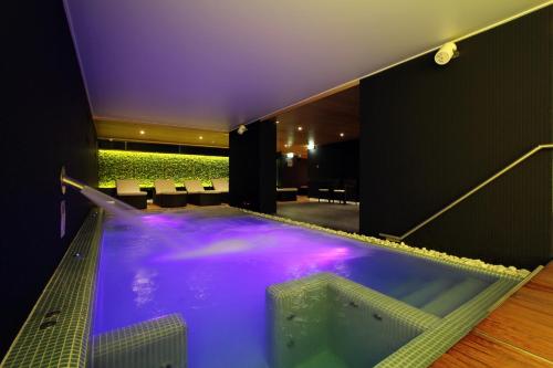 赫维兹美容与购物中心泽纳酒店的一座带紫色照明的建筑里的大型按摩浴缸