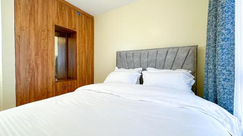 内罗毕Sherrine Homes的卧室配有一张白色大床和灰色床头板