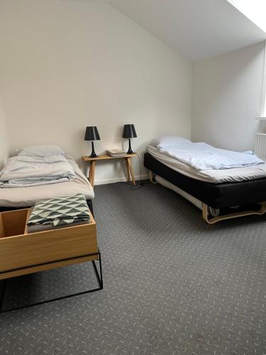 海宁Skøn centralt beliggende lejlighed m.tagterrasse的带2张桌子的客房内的2张单人床