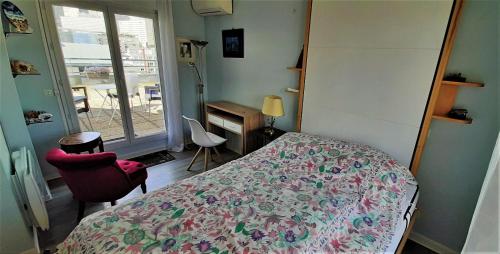 皮托Appartement avec Terrasse à Puteaux 92的一间卧室配有一张床、一张书桌和一个窗户。