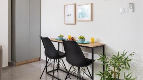 埃拉特By Eezy - אורה דירות אירוח的一张桌子和两张黑色椅子
