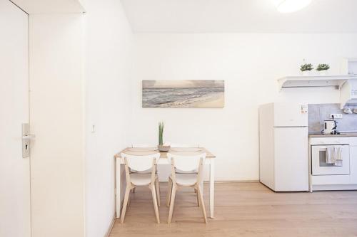 多特蒙德DO One Bedroom Flat的白色的厨房配有桌子和两把椅子
