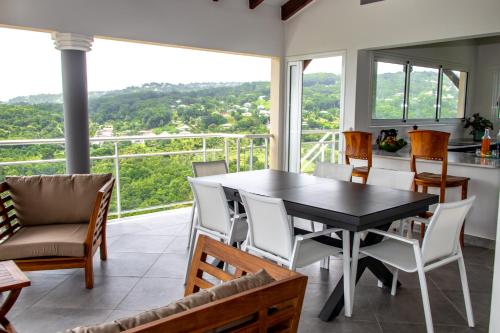 圣吕斯Villa Grenade (haut) - Vue mer et Fort-De-France的一间带桌椅和大窗户的用餐室
