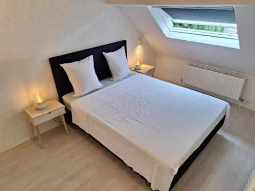 梅赫伦Huis ALNA 3的一间卧室配有一张带2个床头柜的大型白色床