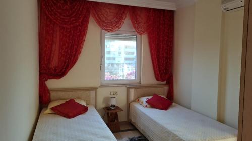 阿拉尼亚VILLA KOHLER的配有红色窗帘和窗户的客房内的两张床