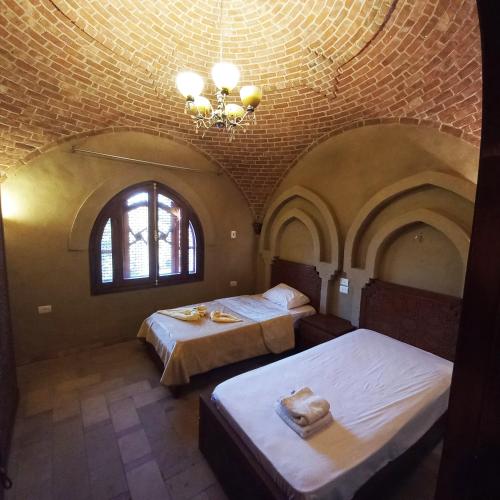 卢克索Mystical habou domes villa的一间卧室配有两张床和吊灯。