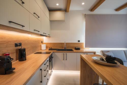 沃洛斯Palaia Luxury Suite的厨房配有白色橱柜和木制台面