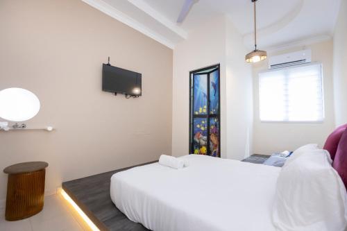 乔治市The Bahari Lodge @ Georgetown的白色卧室设有一张床和墙上的电视