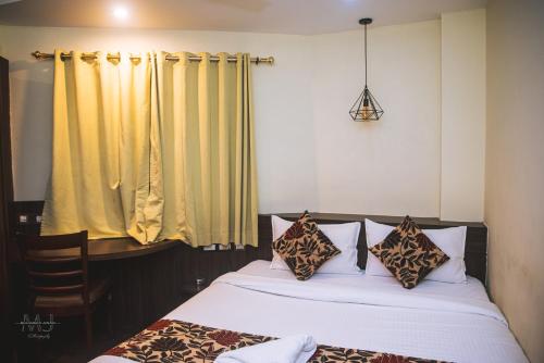 西里古里Rajdarbar Hotel & Banquet, Siliguri的一间卧室设有两张床和黄色窗帘